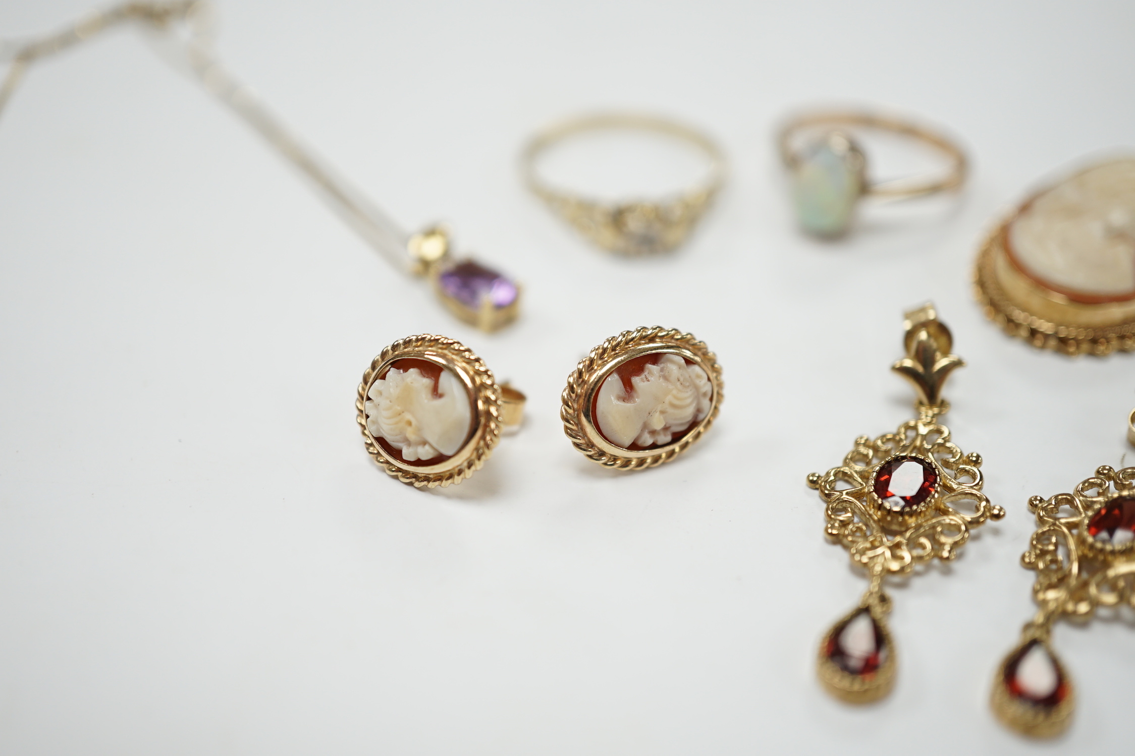 Two 9ct and gem set rings, including diamond chip and white opal, a 9ct and amethyst set pendant necklace, pair of 9ct gold and garnet earrings, a 9ct mounted cameo shell brooch and pair of matching earrings, gross weigh